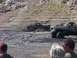 2000 Ford F-450 - Several trucks are navigating a challenging muddy landscape, with onlookers observing the event.