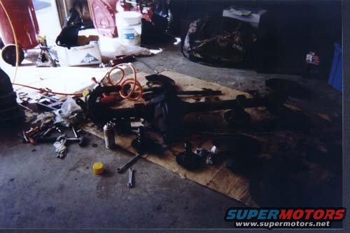 Vehicle axle assembly and tools scattered on a garage floor