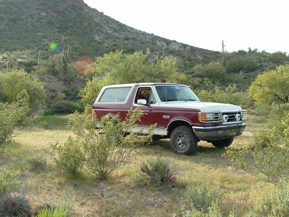 Red and white 1990 Ford Bronco parked in a desert landscape