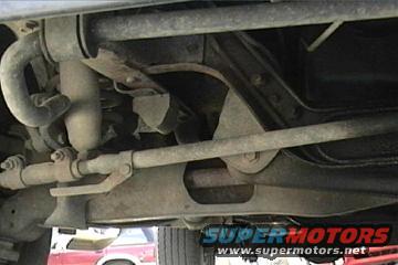 Undercarriage steering and suspension components. Red vehicle visible