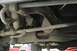 1989 Ford Bronco - Close-up view of the undercarriage, showing steering and suspension parts. Another vehicle is partially visible in the background.