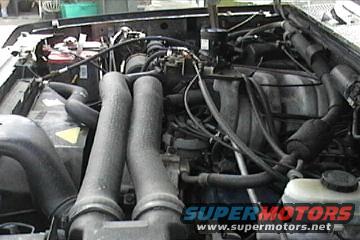 Engine bay with hoses and wiring visible, SuperMotors logo at bottom right