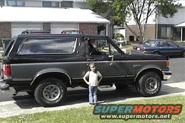 1989 Ford Bronco parked on a residential street, child standing by the driver's side door