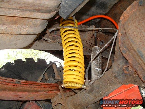 Rear suspension part with yellow coilover shock and orange line