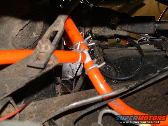 Orange hoses with metal clamps in engine bay, some text visible on hose