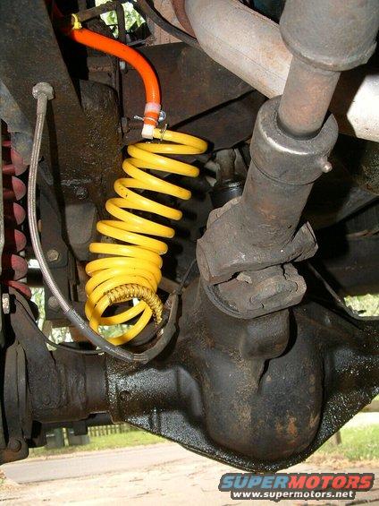 Yellow coiled hose attached to orange tubing above a differential and driveshaft