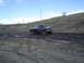 1981 Ford Bronco - Pickup truck navigates a challenging muddy terrain under a partly cloudy sky.