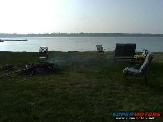 Lakeside scene with chairs and a campfire