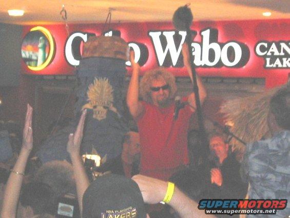 Sammy Hagar in red shirt, sunglasses, performing on stage at Cabo Wabo. Crowd is visible