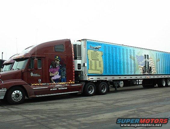 Maroon semi-truck cab with mural of a man holding a child, pulling a trailer with 9/11 memorial graphics