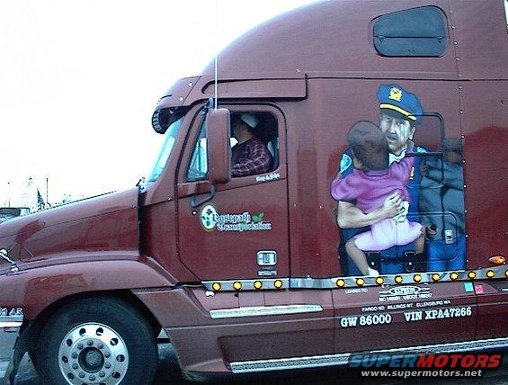 Side view of a maroon semi-truck with a mural of a police officer holding a child painted on the side. Text on the truck includes 'Rosepath Transportation', 'GW 86000', and 'VIN XPA47266'
