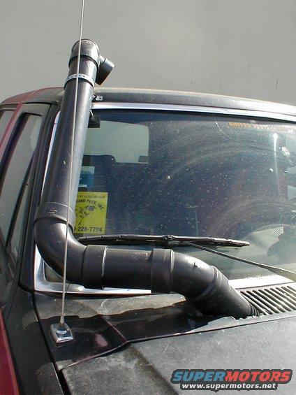 Black snorkel on a dark-colored vehicle's windshield and hood, with a yellow sticker on the window