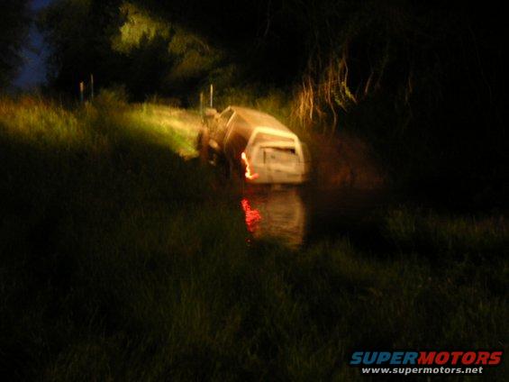 White SUV stuck in water at night, rear view