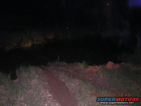 Dark outdoor scene at night with faint headlights visible in the distance