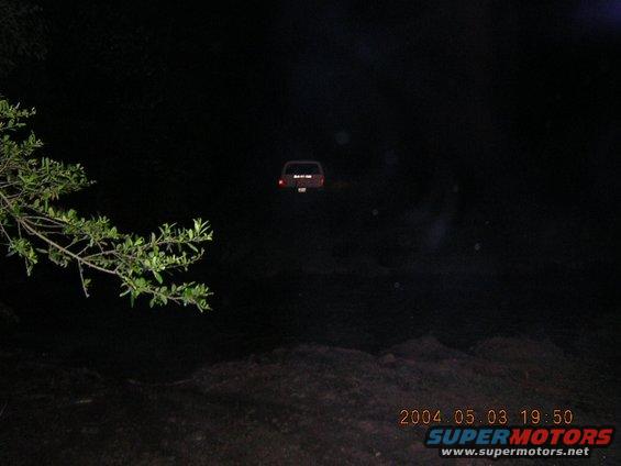red SUV parked in darkness, taillights visible