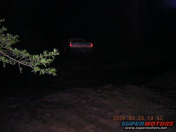 Dark scene with a 1984 Chevrolet pickup truck's rear visible, taillights illuminated