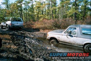 Silver SUV stuck in mud, being pulled by another vehicle