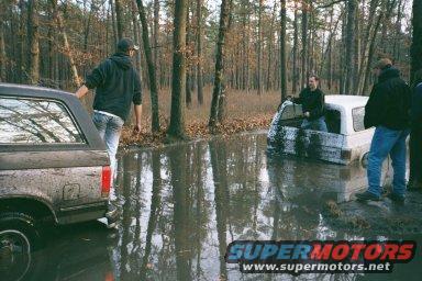 Two SUVs stuck in a muddy wooded area