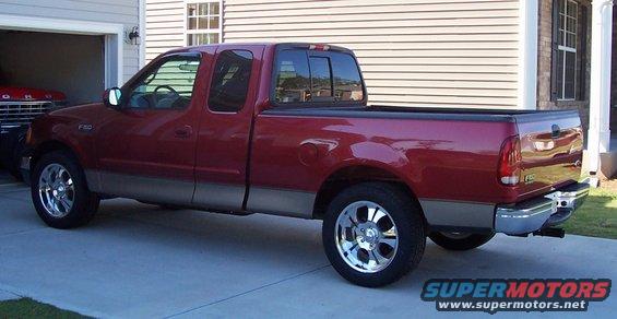 Red pickup truck parked in front of a garage. Another vehicle is partially visible inside the garage