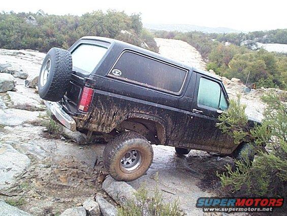 Black Ford Bronco with spare tire on back, navigating rocky terrain