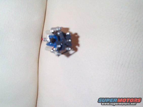 Small toy engine model with blue and silver parts on a light-colored textured surface