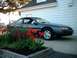 1996 Ford Thunderbird - A dark blue coupe is parked in front of a white house, with a flower bed in the foreground.