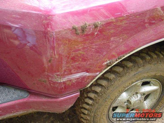 Mud-splattered red truck rear fender and tire