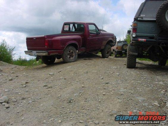 Red 1992 Ford F-150 pickup truck, rear 3/4 view, parked on a gravel road