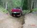 1992 Ford F-150 - A red 1992 Ford F-150 navigates a challenging off-road trail through a wooded area.