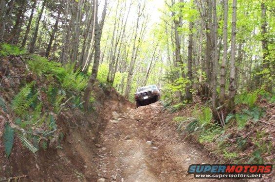 Ford F-150 climbing a steep, rocky dirt road in a forest