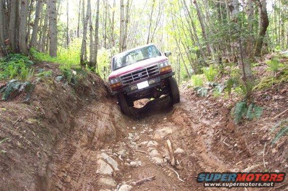 1992 Ford F-150 navigating a steep, muddy off-road trail