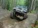 1992 Ford F-150 - A Jeep CJ-7 navigates a challenging off-road trail surrounded by trees.