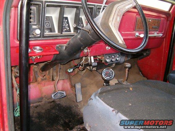 1979 Ford Bronco interior showing dashboard, steering wheel, pedals, and aftermarket gauges