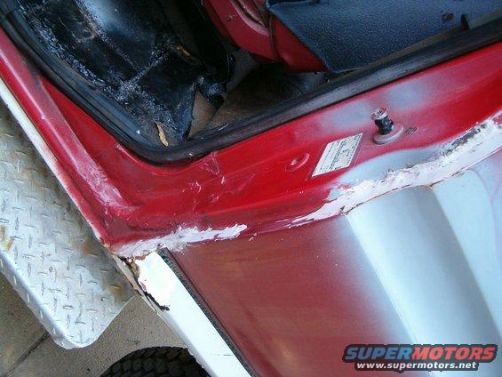 close-up of red vehicle door jamb with some rust and body filler