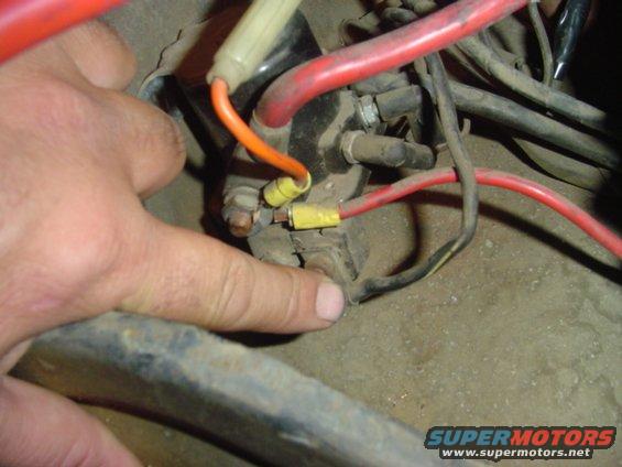 Close-up of starter solenoid wiring with a finger pointing to a connection