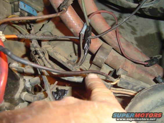 Close-up of engine bay wiring with a finger pointing to a connection
