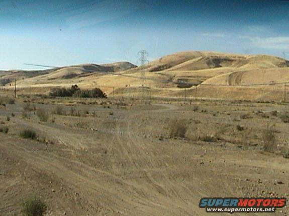 Desert landscape with power lines and a dirt road