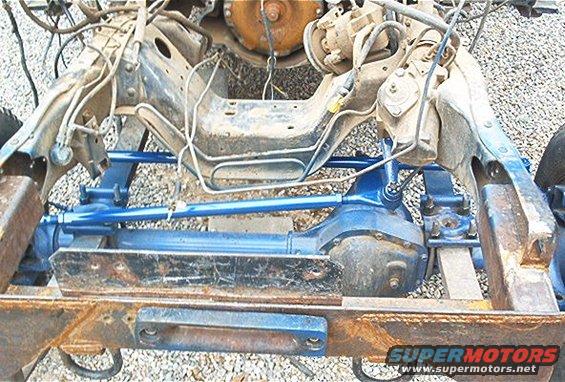 Vehicle chassis with blue-painted steering components and differential. Rusty frame rails visible