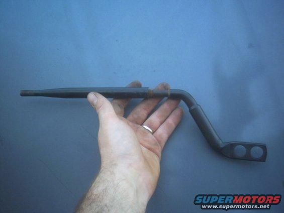 Hand holding a bent metal rod with two circular holes at one end