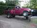 1992 Ford F-150 - A red 1992 Ford F-150 pickup truck is shown with its front wheels elevated on a ramp and log.
