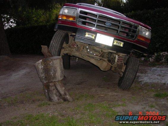 1992 Ford F-150 front end angled over a large wooden log obstacle