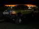 2000 Ford F-450 - A lifted gold Ford F-Series truck is parked at a gas station at night, with another vehicle visible behind it.