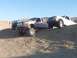2000 Ford F-450 - Three lifted trucks, including a 2000 Ford F-450, navigate sandy terrain under a clear blue sky.