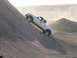 2000 Ford F-450 - A white pickup truck navigates a challenging incline on a dusty, barren landscape.