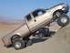2000 Ford F-450 - A lifted pickup truck navigates a sandy hill, with another truck visible in the background.