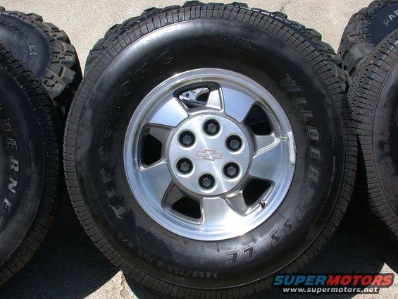 Four tires and wheels, one with a Chevrolet logo on the hub