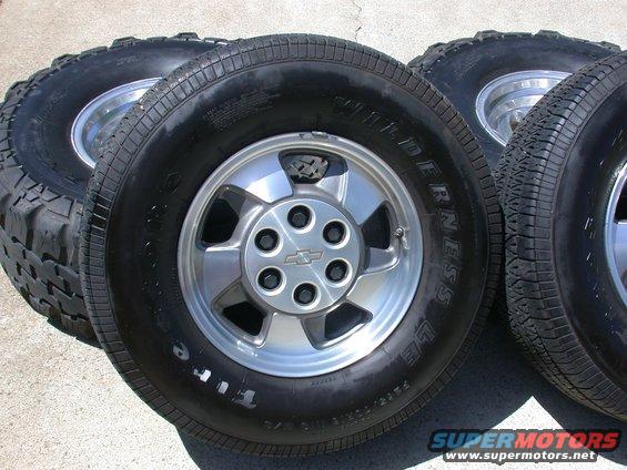 Four tires with Chevrolet rims. One tire has white lettering
