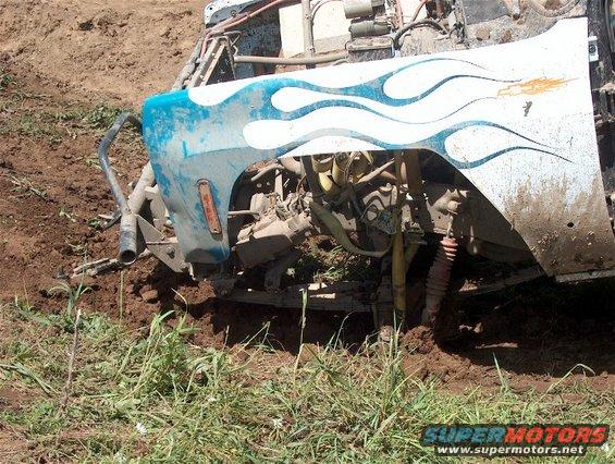 Off-road vehicle with blue flames graphic stuck in mud, showing front fender and engine components