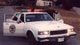 White police car, 3/4 front view. Appears to be a 1995 Ford Crown Victoria