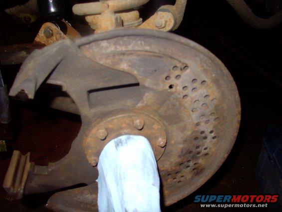 Brushed off 19 years of asbestos to reveal a rusty, but pretty solid dust shield. Leave a rag over the spindle shaft.